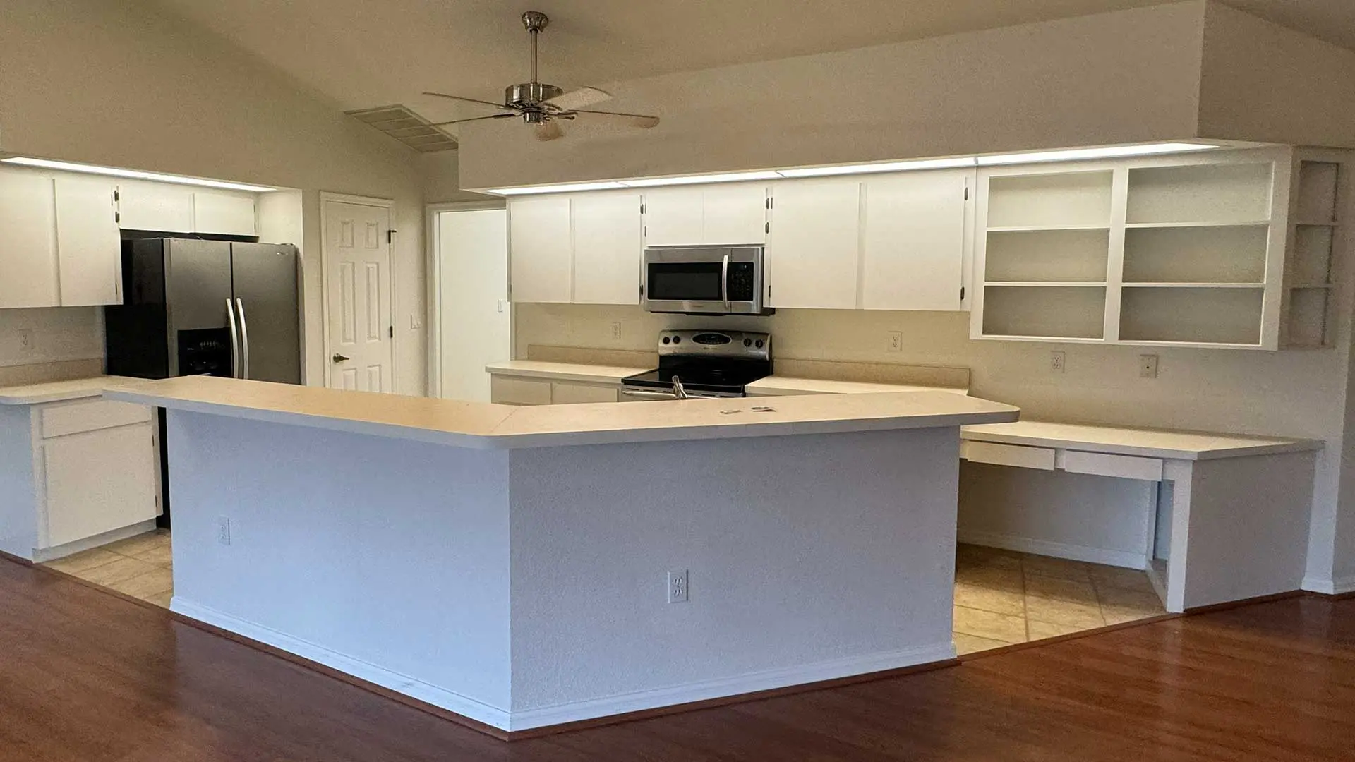 spacious open-concept kitchen featuring newly finished white cabinets, a large wrap-around breakfast bar peninsula, and stainless steel appliances