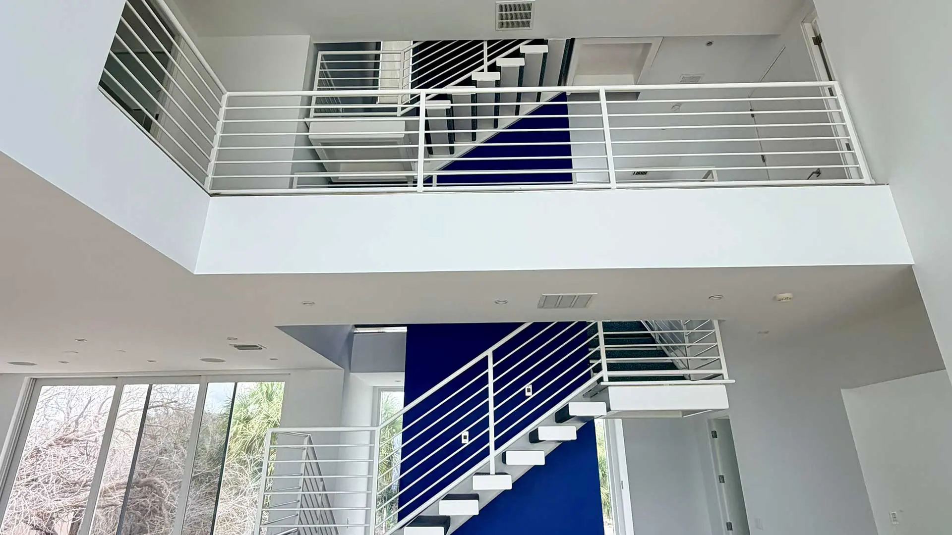 white multi-level staircase wraps around a striking royal blue wall