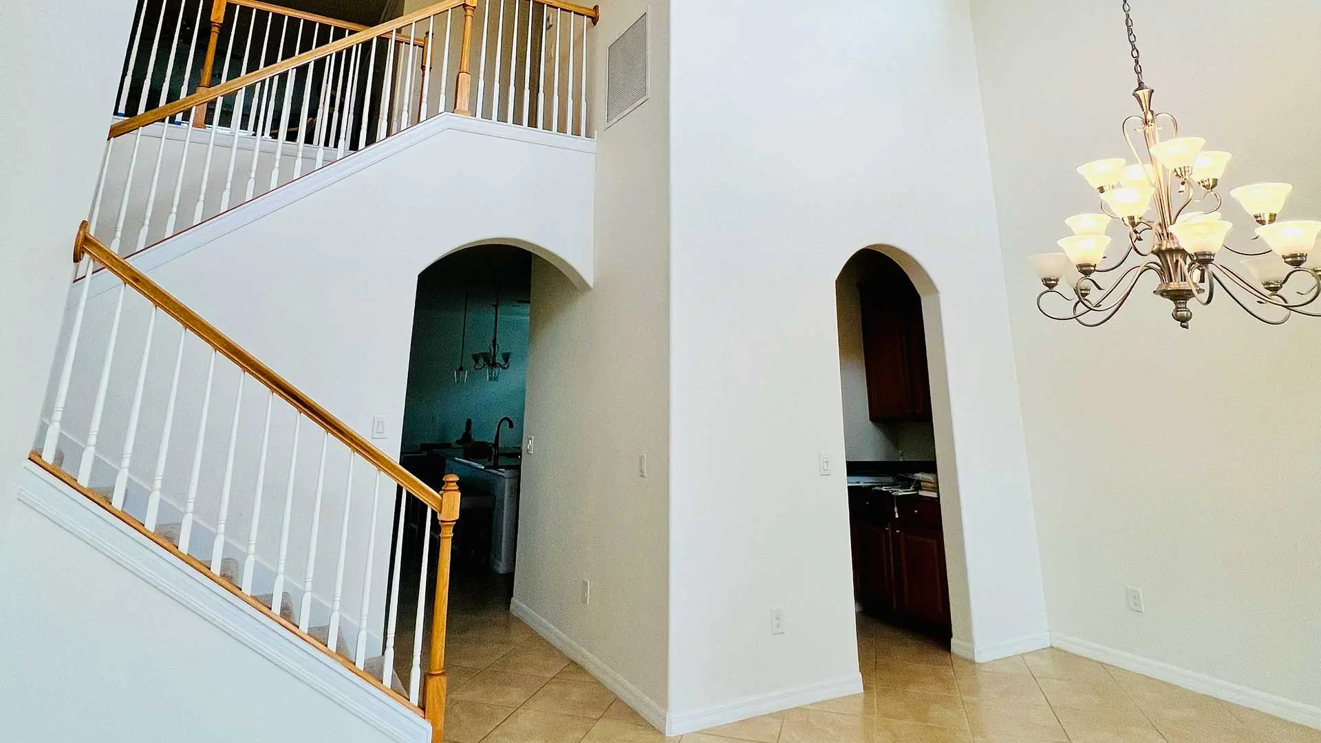 high-ceiling foyer with white walls, arched doorways, and staircase