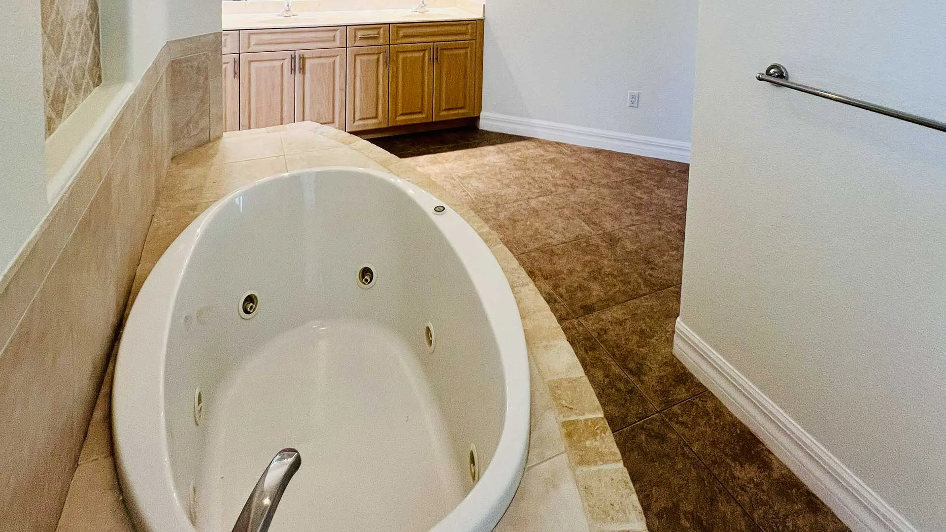 large oval soaking tub surrounded by beige tile in bathroom