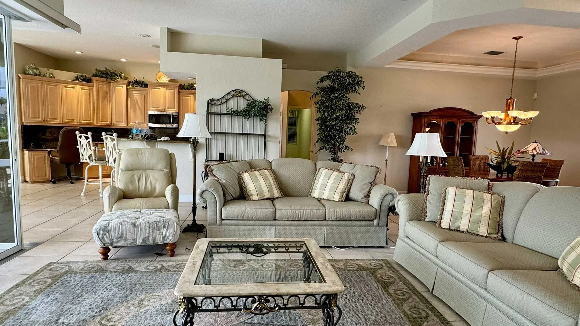 spacious open-concept living area with light-colored sofas and kitchen