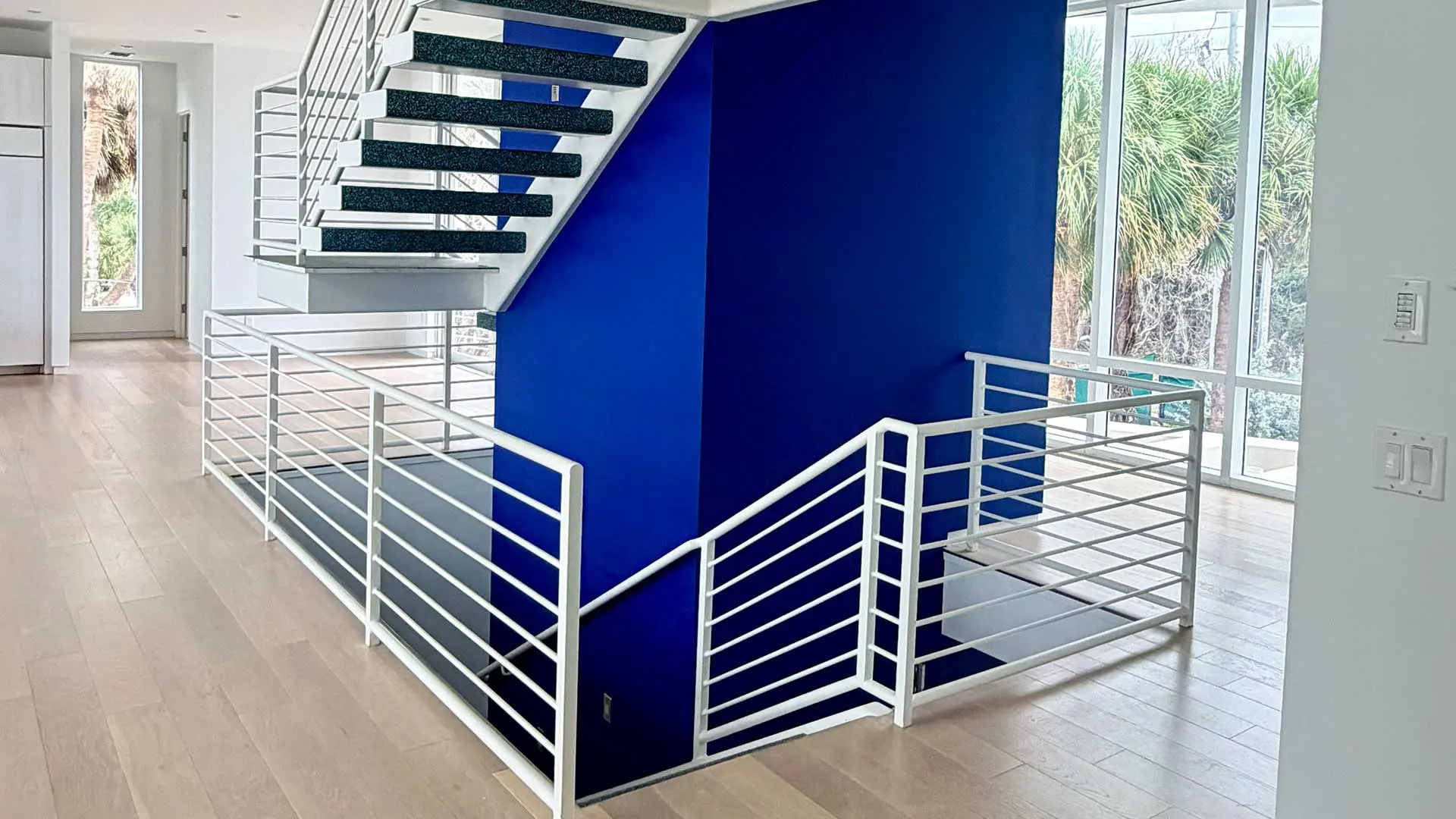 modern staircase with white metal railings against royal blue wall