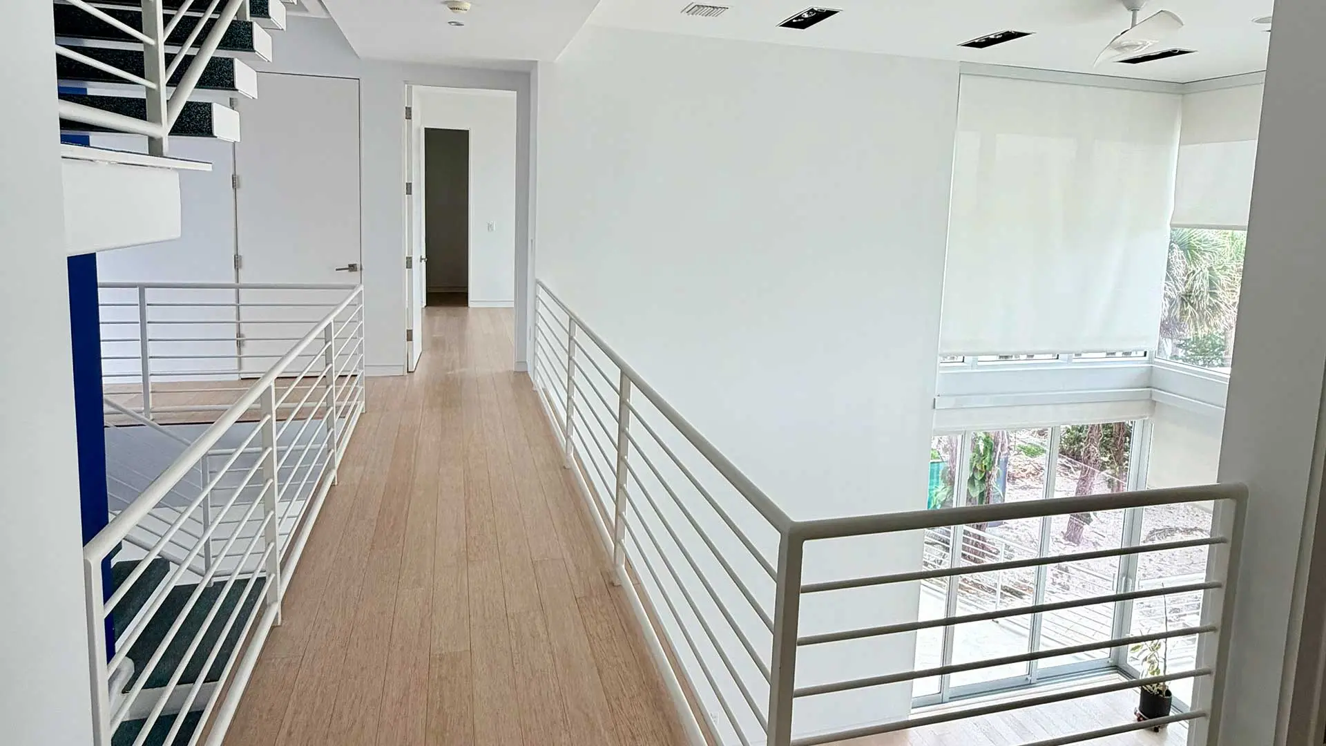 bright upstairs hallway with wood flooring and white safety railings