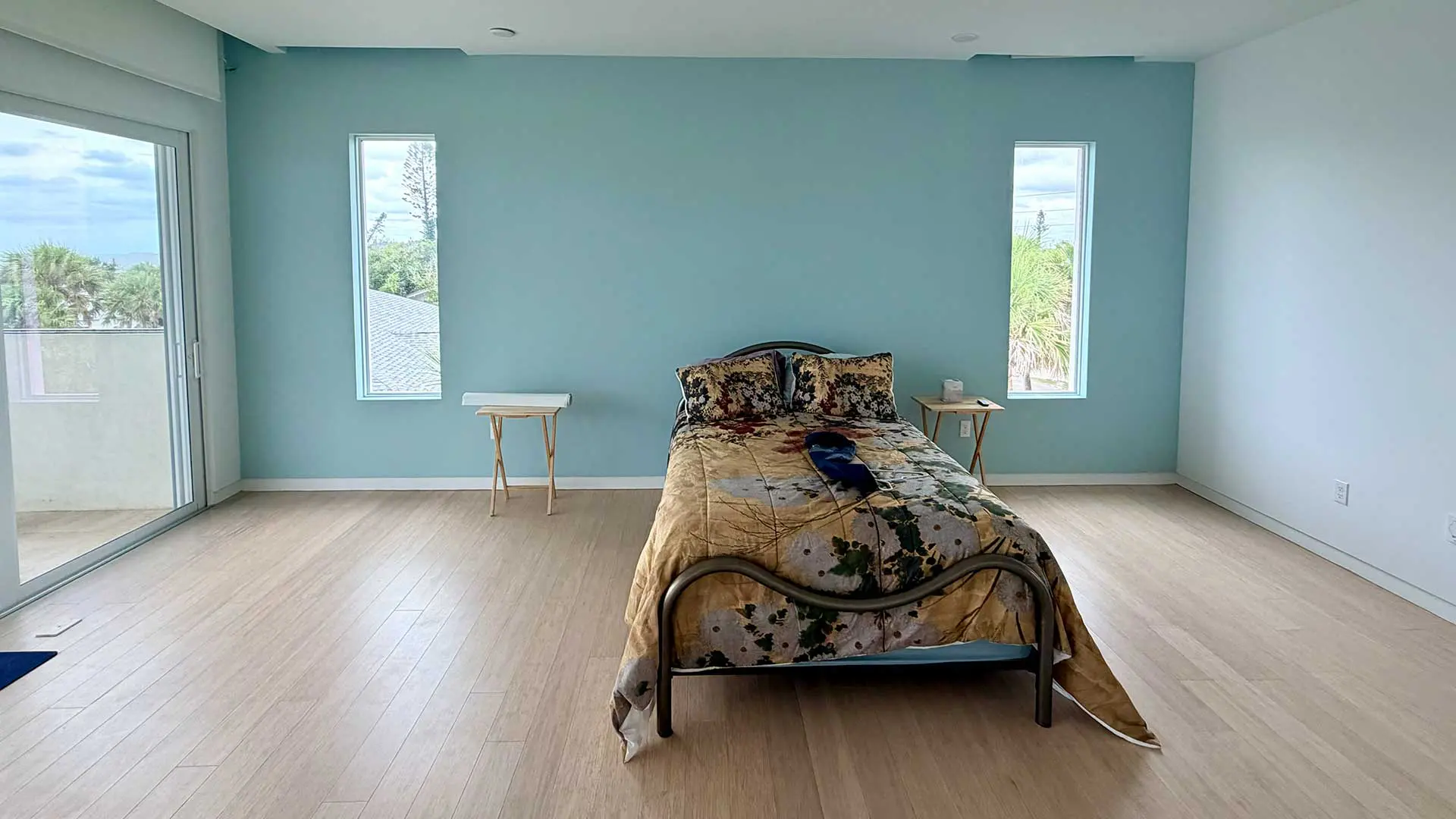 minimalist bedroom featuring light blue accent wall and large windows