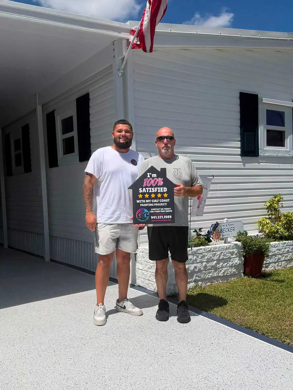 Painting contractor and satisfied customer standing side-by-side holding a 5-star review sign outside a completed exterior project