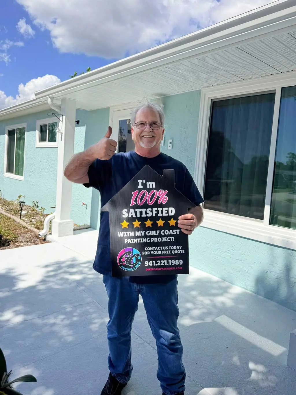 Happy client giving a thumbs up while holding a 100% satisfied customer sign in front of painted home siding