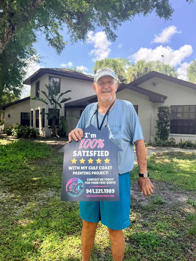 Happy client standing outside a refreshed residential home holding a customer satisfaction review sign