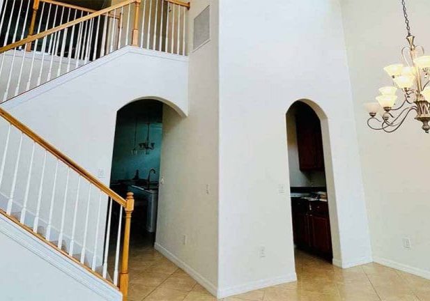 high-ceiling foyer with white walls, arched doorways, and staircase